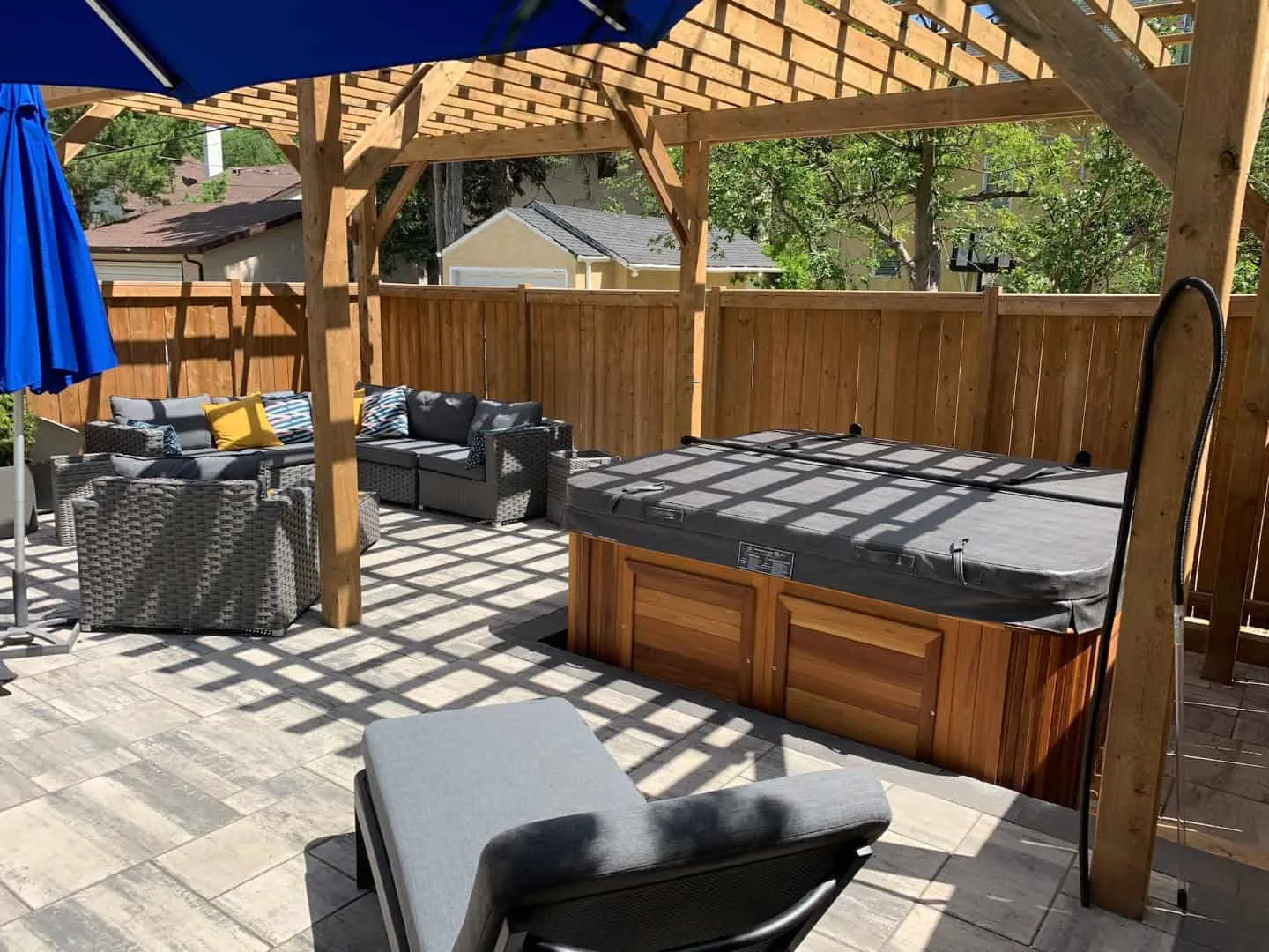 Timber-framed pergola over a paver patio with a sunken hot tub