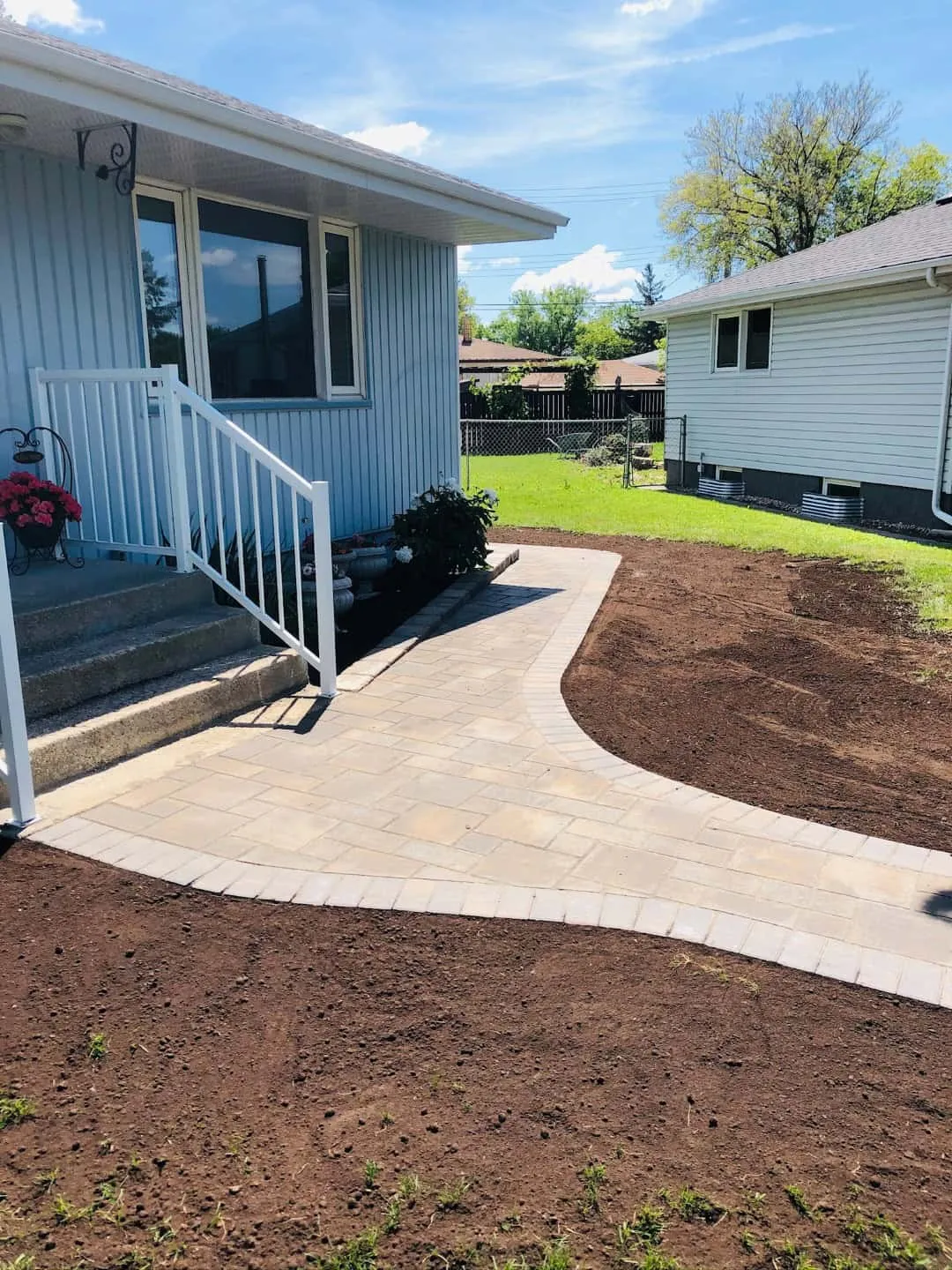 Curved sandstone paver walkway and landing with a soldier-course border, laid across a freshly graded front yard