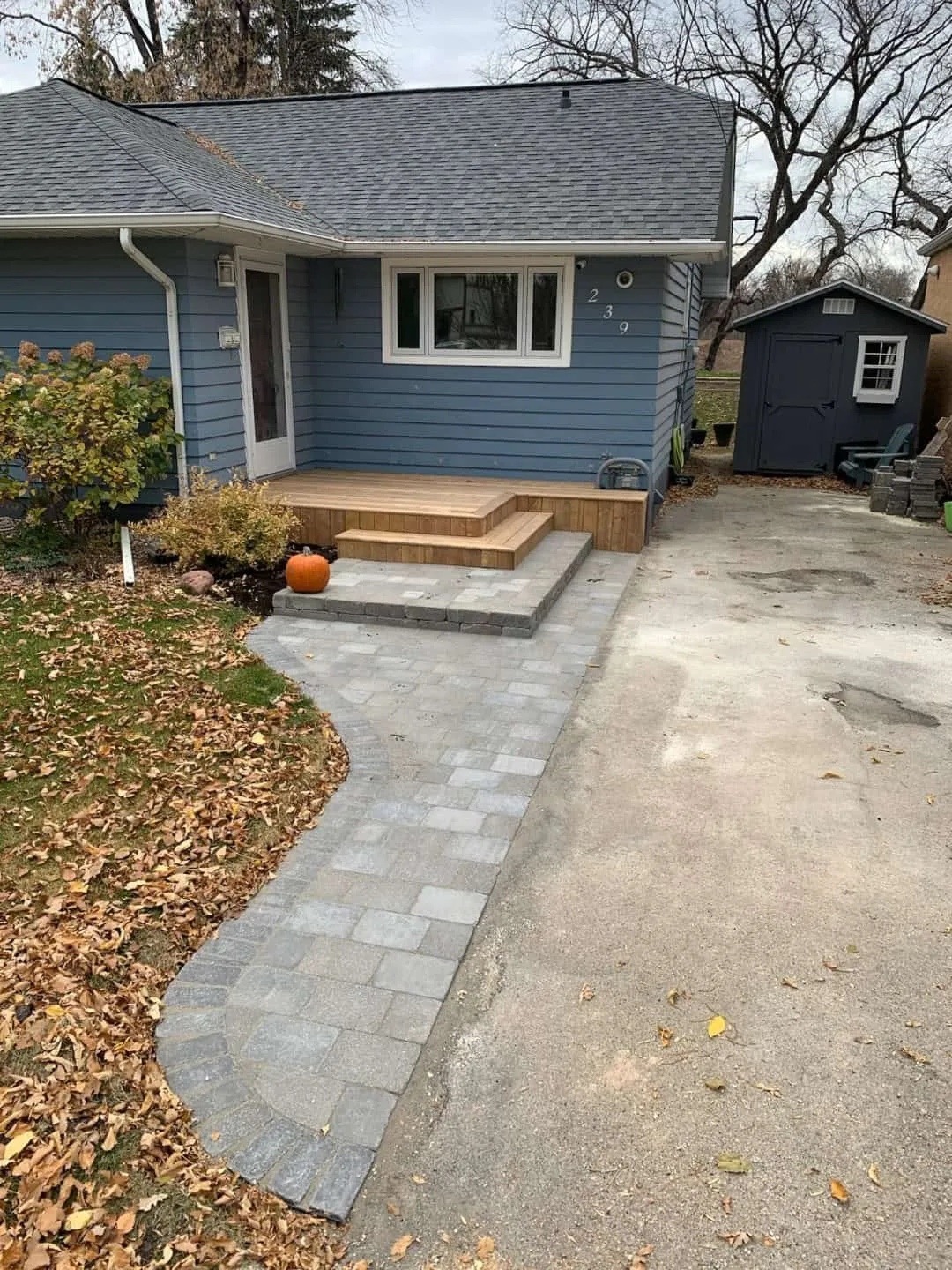 Grey paver walkway and landing with a charcoal soldier border leading to cedar steps at a front door